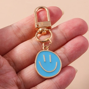 Porte-clés visage souriant en émail bleu ciel avec fermoir mousqueton doré