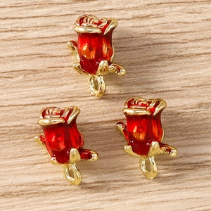 Macro detail of three red enamel rose pendants with gold base for DIY jewelry making