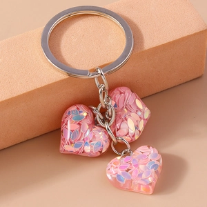 Détail des porte-clés en résine en forme de cœur avec paillettes roses et métal