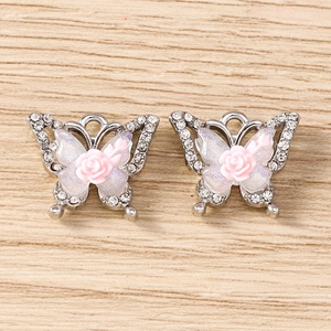 Detailed view of silver rhinestone butterfly charms with pink rose centers and pearl wings