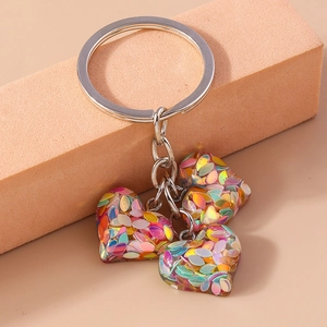Détail de breloques cœur en résine avec paillettes irisées sur un porte-clés argenté