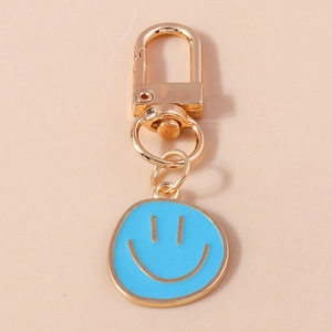 Détail du porte-clés en métal doré avec pendentif smiley bleu en émail brillant