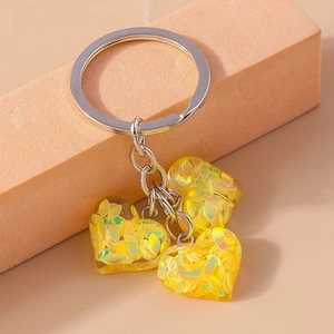 Vue macro de pendentifs en cœur transparents avec paillettes jaunes sur mousse orange