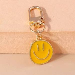 Macro d'un pendentif smiley en émail jaune avec un anneau porte-clés en métal doré