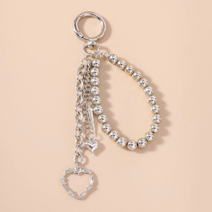 Close-up of punk style silver keychain with metal beads and thorn heart pendant charms