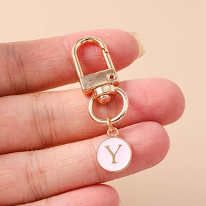 Close-up of pink enamel round pendant with golden letter Y on a metal keychain hook