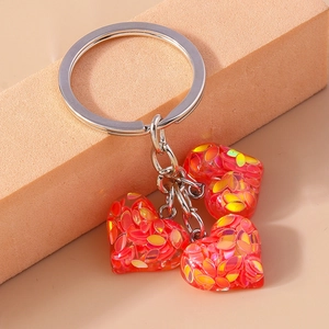 Vue détaillée de trois pendentifs en cœur sur un porte-clés en argent avec résine à paillettes