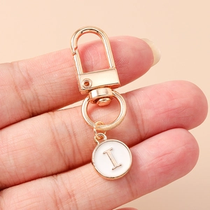 Close-up of golden letter I charm with white enamel on a polished lobster clasp keychain