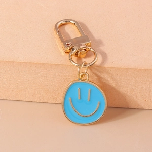 Détail d'un porte-clés pendentif smiley en émail bleu ciel avec fermoir mousqueton doré