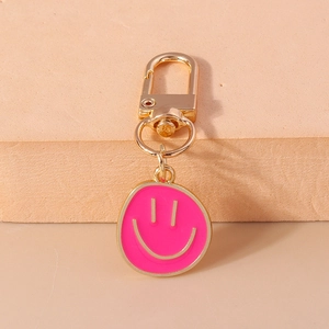 Gros plan d'un porte-clés smiley en émail rose avec un fermoir mousqueton doré