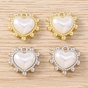 Vista macro di ciondoli a cuore irregolari con perle bianche in finiture oro e argento
