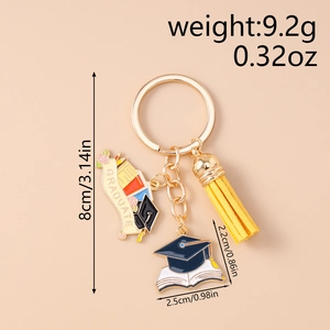 Detail of graduation keychain with graduate scroll and mortarboard charm on pink background