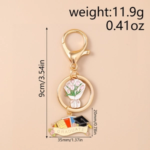Close-up of golden graduation keychain with pink tulip charm and graduate banner detail