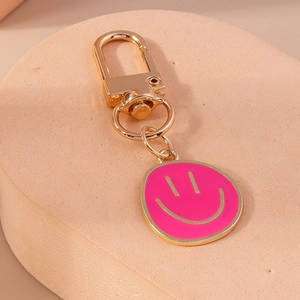 Détail d'un porte-clés smiley en émail rose avec clip et anneau en métal doré
