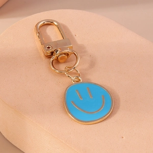 Détail du pendentif sourire en émail bleu avec crochet porte-clés doré sur surface