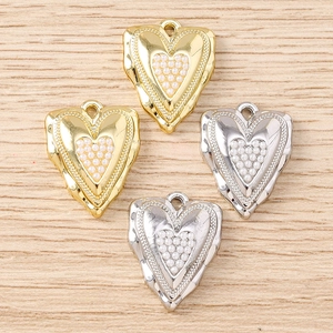 Dettaglio di ciondoli a cuore irregolari con perle incastonate e bordi in metallo