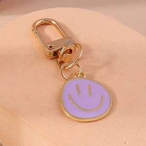Gros plan sur un porte-clés émaillé violet avec un visage souriant et anneau doré