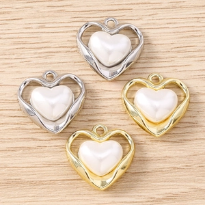 Vista macro di ciondoli a cuore in oro e argento con intarsio in perla bianca per gioielli fai-da-te