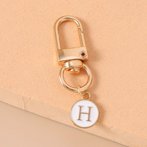 Close-up of golden letter H charm pendant with white enamel finish on creative lobster clasp