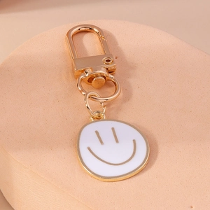 Gros plan détaillé du porte-clés doré avec pendentif émaillé en forme de smiley