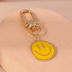 Gros plan d'un porte-clés smiley jaune avec un fermoir mousqueton doré sur un support