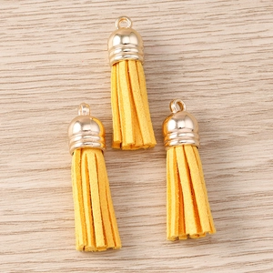 Close-up of yellow suede tassels with golden metal caps for DIY jewelry and keychains