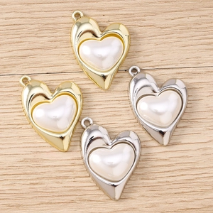 Dettaglio di ciondoli a cuore irregolari con cornici in oro e argento e perle bianche