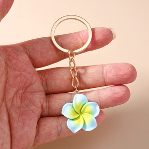 Close-up of yellow and blue gradient resin plumeria flower keychain with golden ring
