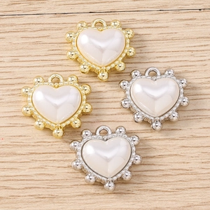 Dettaglio di ciondoli a cuore in perla con bordi metallici a sfere dorate e argentate