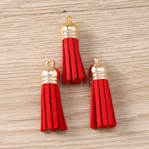 Three red velvet tassel pendants with golden metal caps on a light wood background