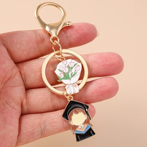 Detail of a gold graduation keychain with enamel bouquet and cartoon graduate girl charm
