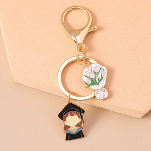 Detail of a graduation keychain featuring a pink tulip bouquet and cartoon female graduate