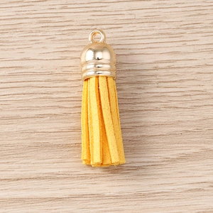 Close-up of a yellow suede tassel pendant with a golden metal cap for DIY jewelry making
