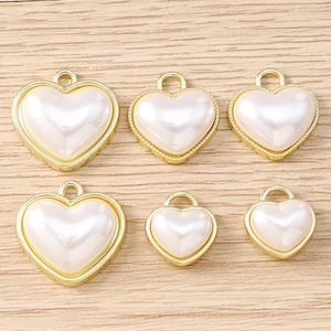 Dettaglio di sei ciondoli a cuore placcati in oro con perle per creazione gioielli fai-da-te