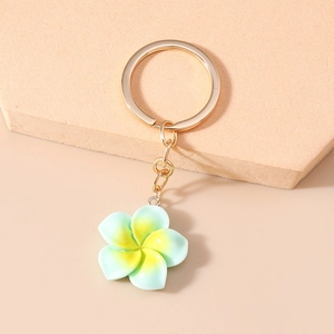 Detail of mint green and yellow gradient frangipani resin keychain on golden hardware