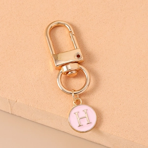 Close-up of pink enamel letter H pendant on golden metal keychain for DIY bag decor