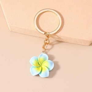 Macro view of blue and yellow gradient resin plumeria flower pendant on golden keychain