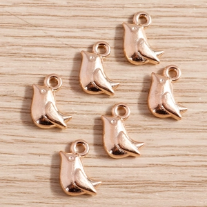 Détails macro de six pendentifs oiseaux polis en or rose avec anneaux pour bijoux DIY