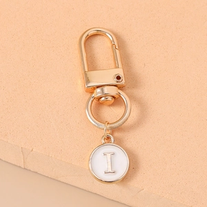 Detail of a gold-plated alphabet charm 'I' with a white enamel finish and lobster clasp