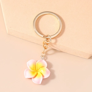 Close-up of frangipani keychain with pink gradient petals and gold metal ring