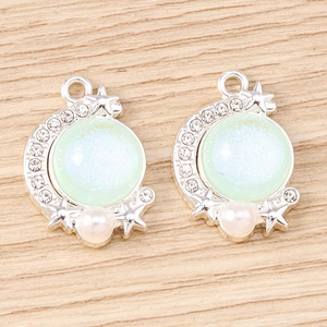 Detail of star and moon jewelry pendants with light green stones and tiny white pearls