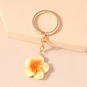 Detail of yellow and orange gradient plumeria flower keychain on textured stone