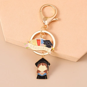 Detail of a gold graduation keychain with enamel graduate girl charm and colorful books