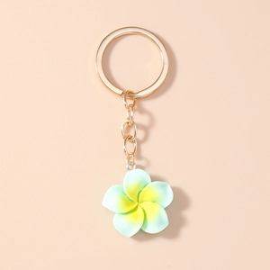 Detail of mint green resin plumeria flower keychain with golden ring on pink background