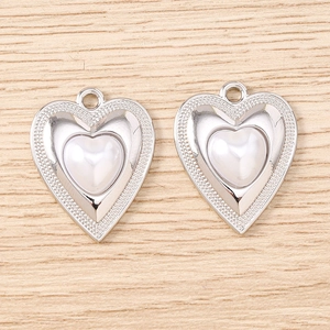 Dettaglio macro di due ciondoli a cuore in perla con bordo in rilievo argentato