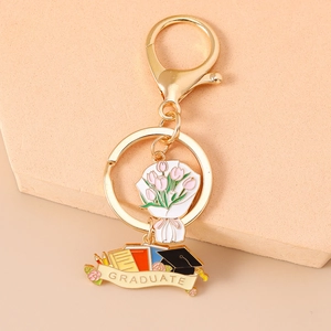 Detailed close-up of golden graduation keychain with pink tulip and graduate cap pendant
