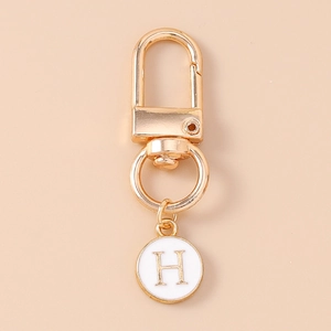 Close-up of golden lobster clasp with white enamel charm featuring the gold letter H