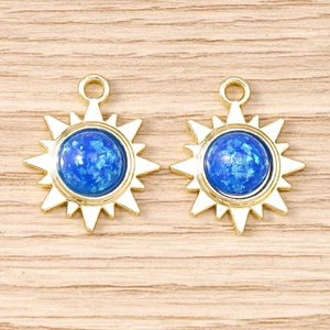 Détail macro de breloques soleil en alliage doré avec opale en résine bleue pour bijoux DIY