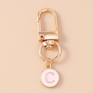 Close-up of pink enamel round pendant with gold letter C and lobster clasp metal keychain