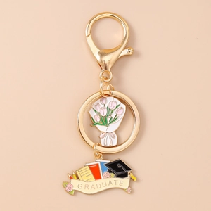 Macro shot of gold-plated graduation keychain with colorful floral bouquet and graduate charm